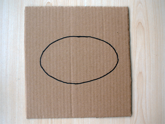 Draw an oval shape on the piece of card